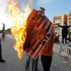 An Iraqi protester outside the US embassy in Baghdad burns an image of US president Donald Trump.